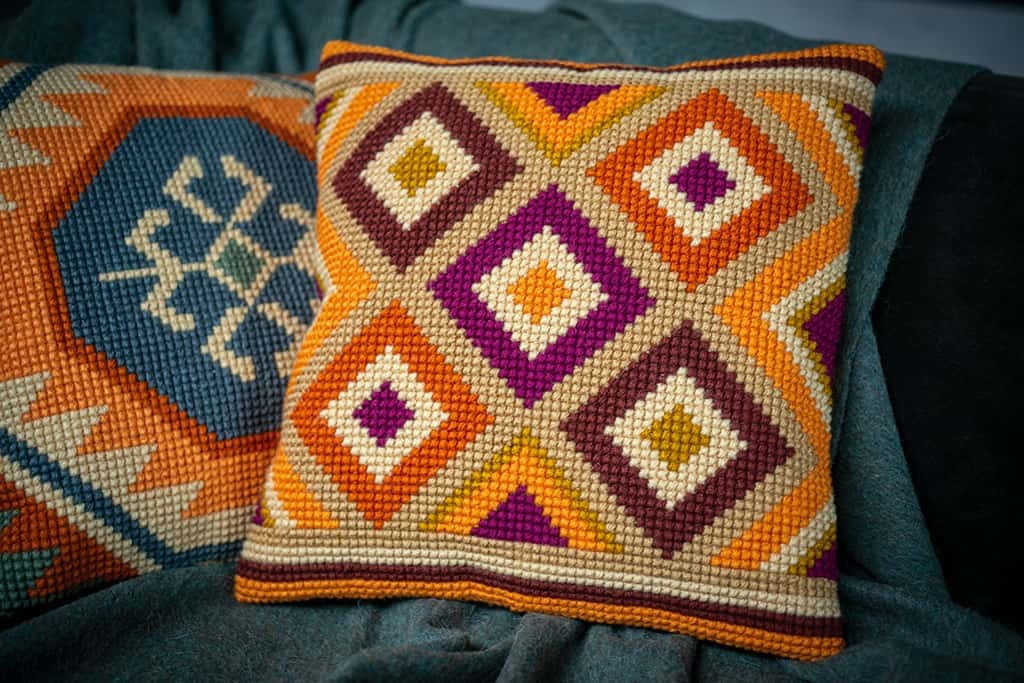 Cuscini ricamati a punto croce con fili di lana, stile geometrico.